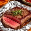 Кусочек красивого мяса лежит в фольге с зеленью